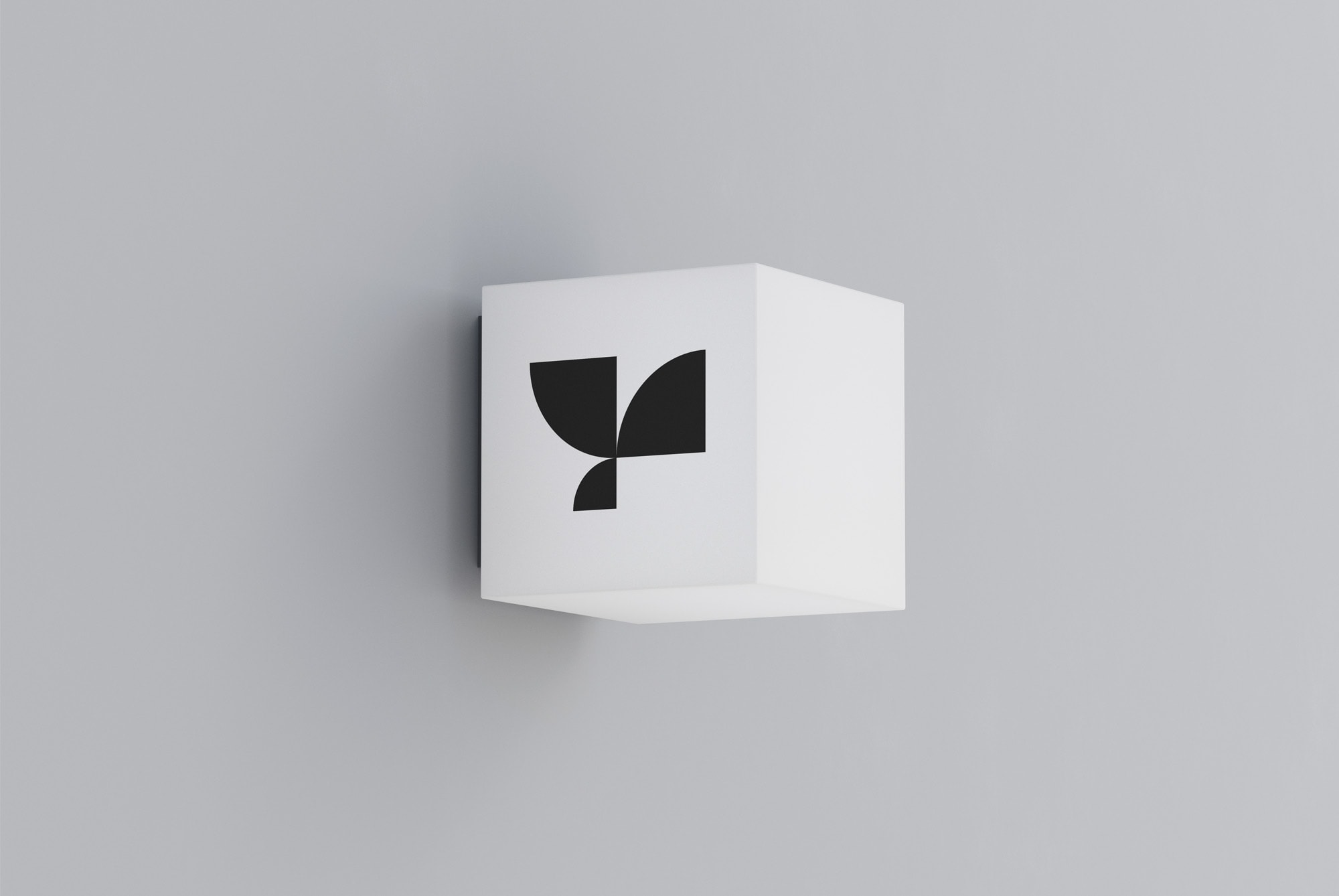 Minimalist logo mockup on white cube against a grey wall, ideal for presenting clean graphic designs or brand identities to clients.