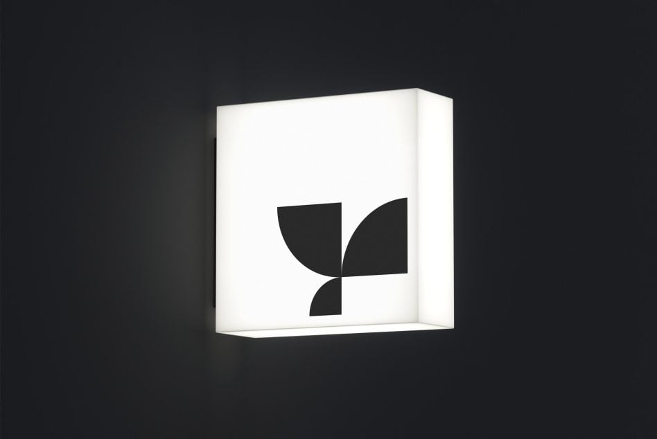 Minimalist leaf mark glowing on lightbox against dark backdrop