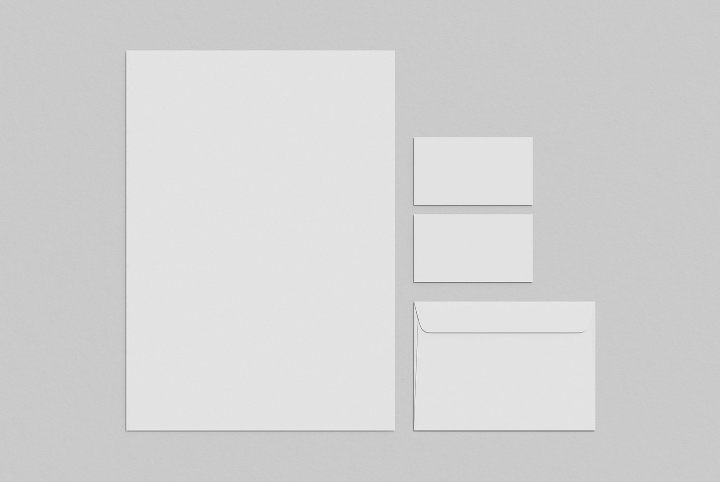 Stationery mockup with A4 paper, business cards, and envelope on a grey background for presentation and portfolio designs.