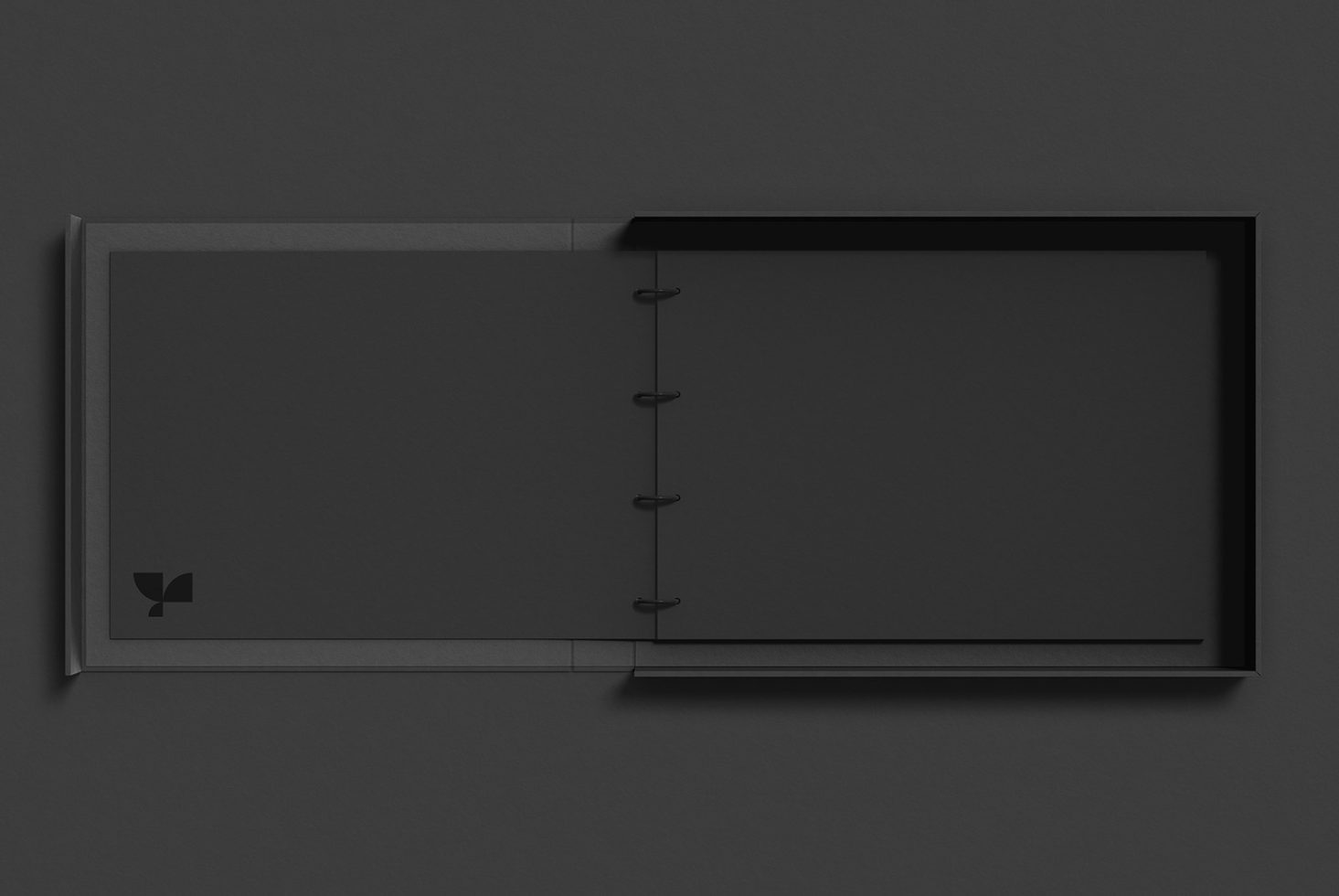 Dark closed notebook with spiral binding down center, minimal branding visible