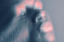 Blurred figure with teal tones, pink neon bokeh lights overlaid softly
