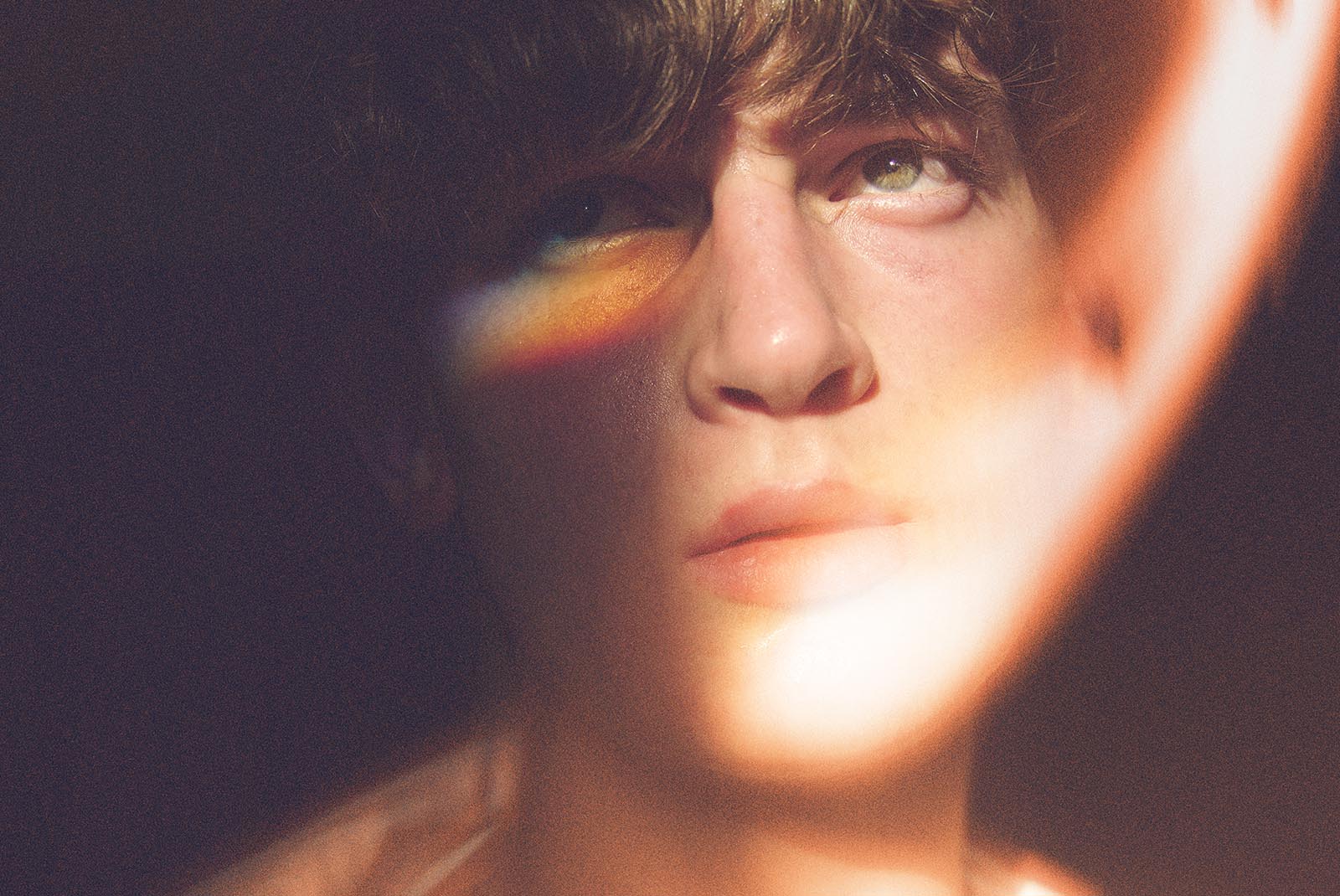 Close-up photo of a person with rainbow light on face for graphic design inspiration or mockup.