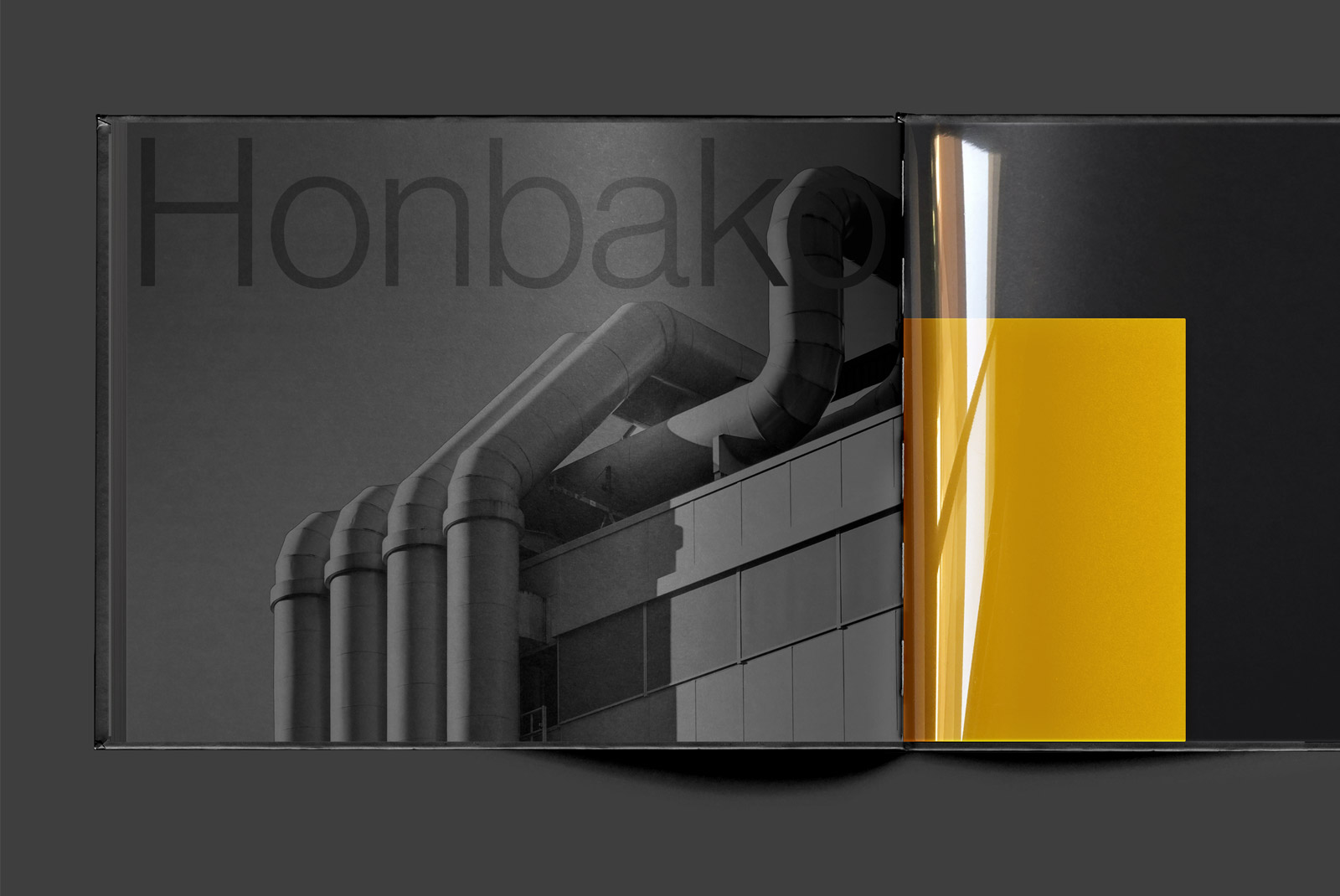 Black book cover mockup with industrial pipes design and partial yellow page, sleek presentation for designers.