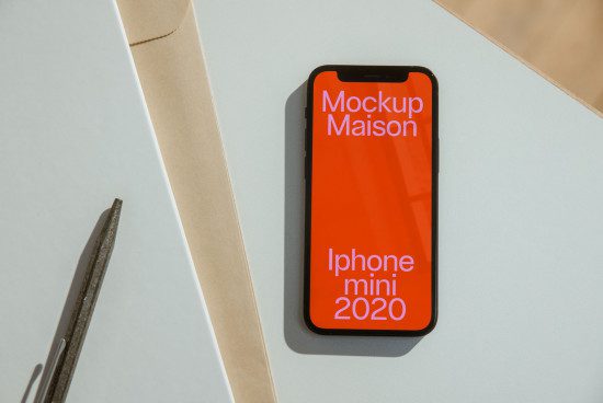 Smartphone mockup on desk with pen and paper, modern digital design mockup, iPhone mini 2020 model display, graphic design mockups.