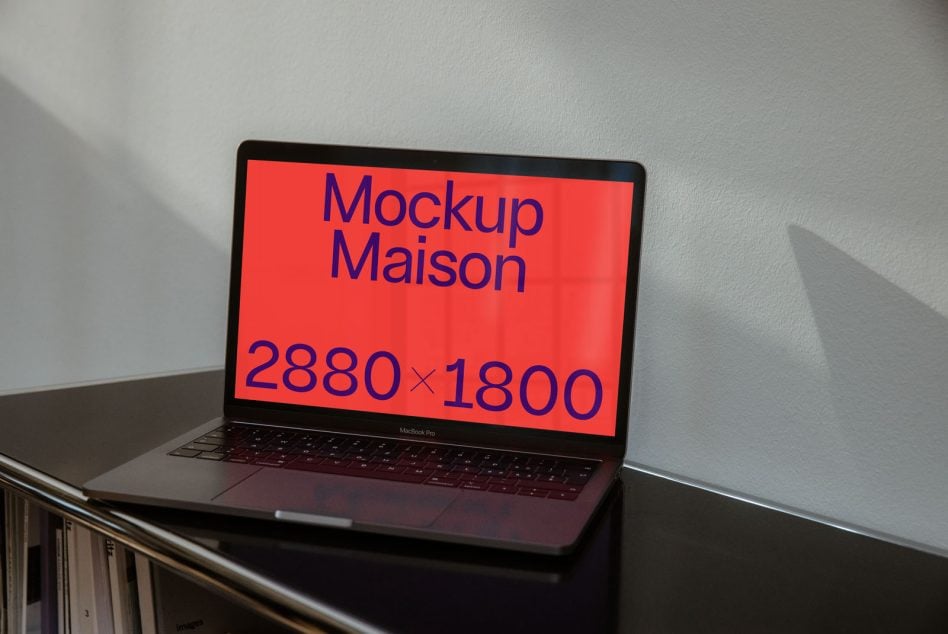 MacBook Pro showing red display with blue mockup text on concrete surface