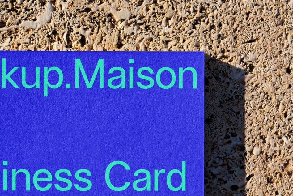 Blue business card mockup with cyan text on textured stone surface