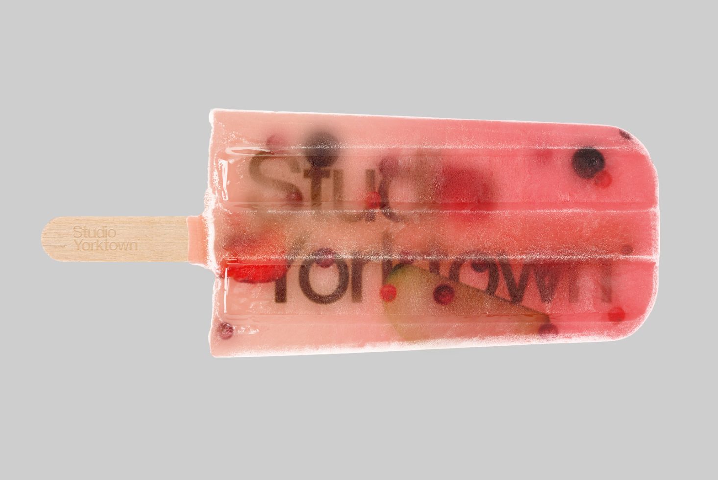 Creative popsicle mockup with transparent fruit-infused design showcasing Studio Yorktown brand, perfect for presentations and packaging.