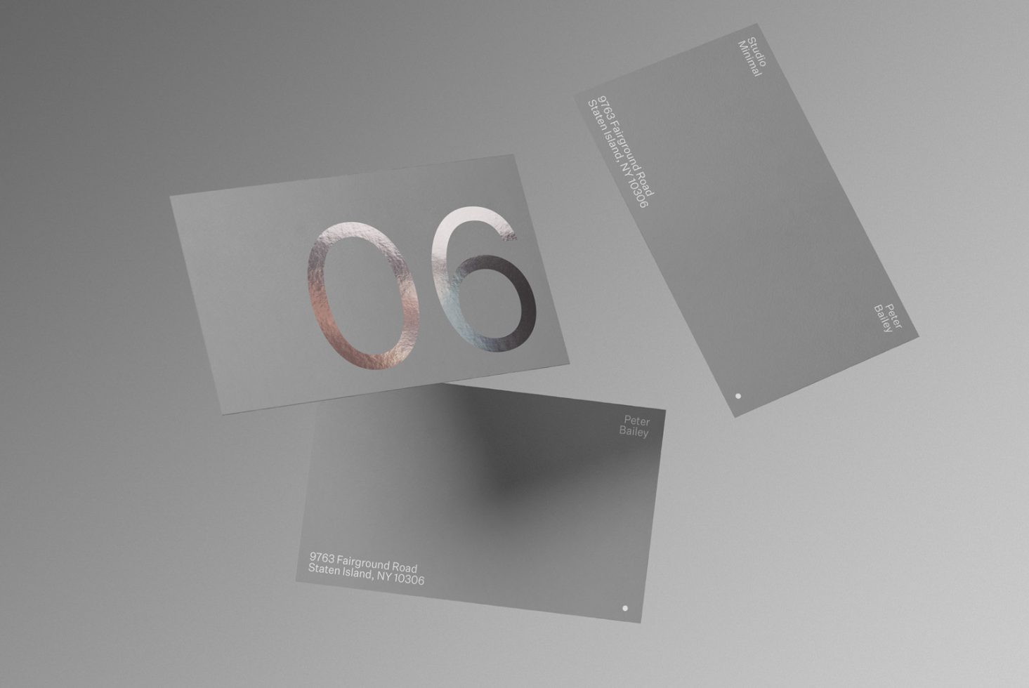 Elegant business card mockup with metallic foil stamping, floating against a gray background, showcasing modern graphic design.