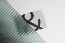Black ampersand symbol pressed onto light card with green ridged surface detail