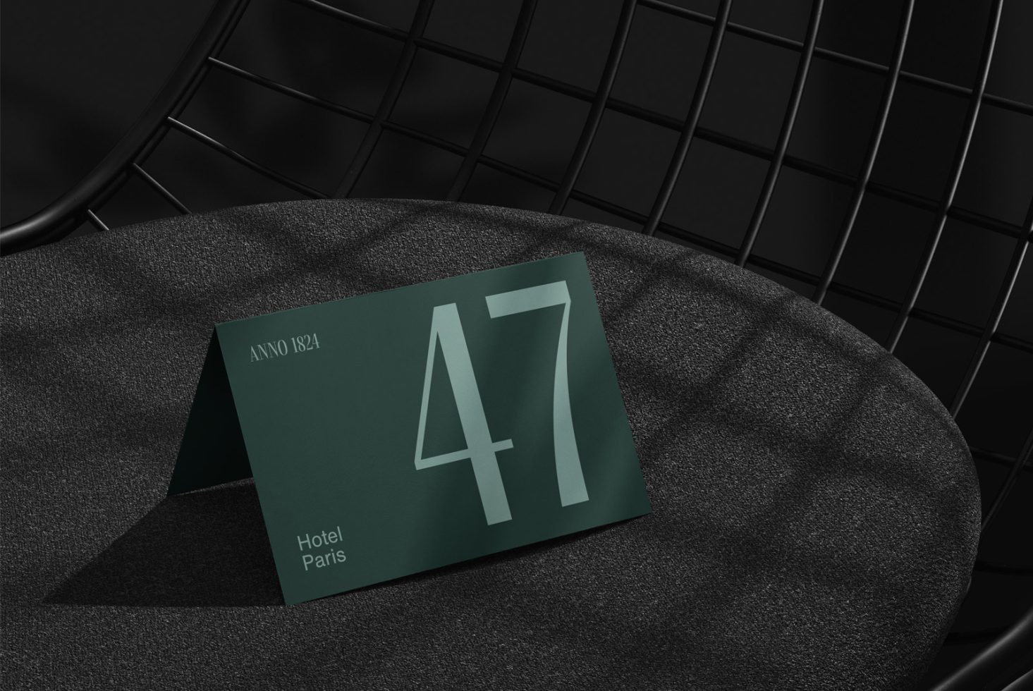 Elegant card design mockup featuring large number 47 on a green background, resting on a textured black chair for branding and presentation.