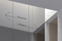 Light marble wayfinding sign with Rooms Library navigation arrows