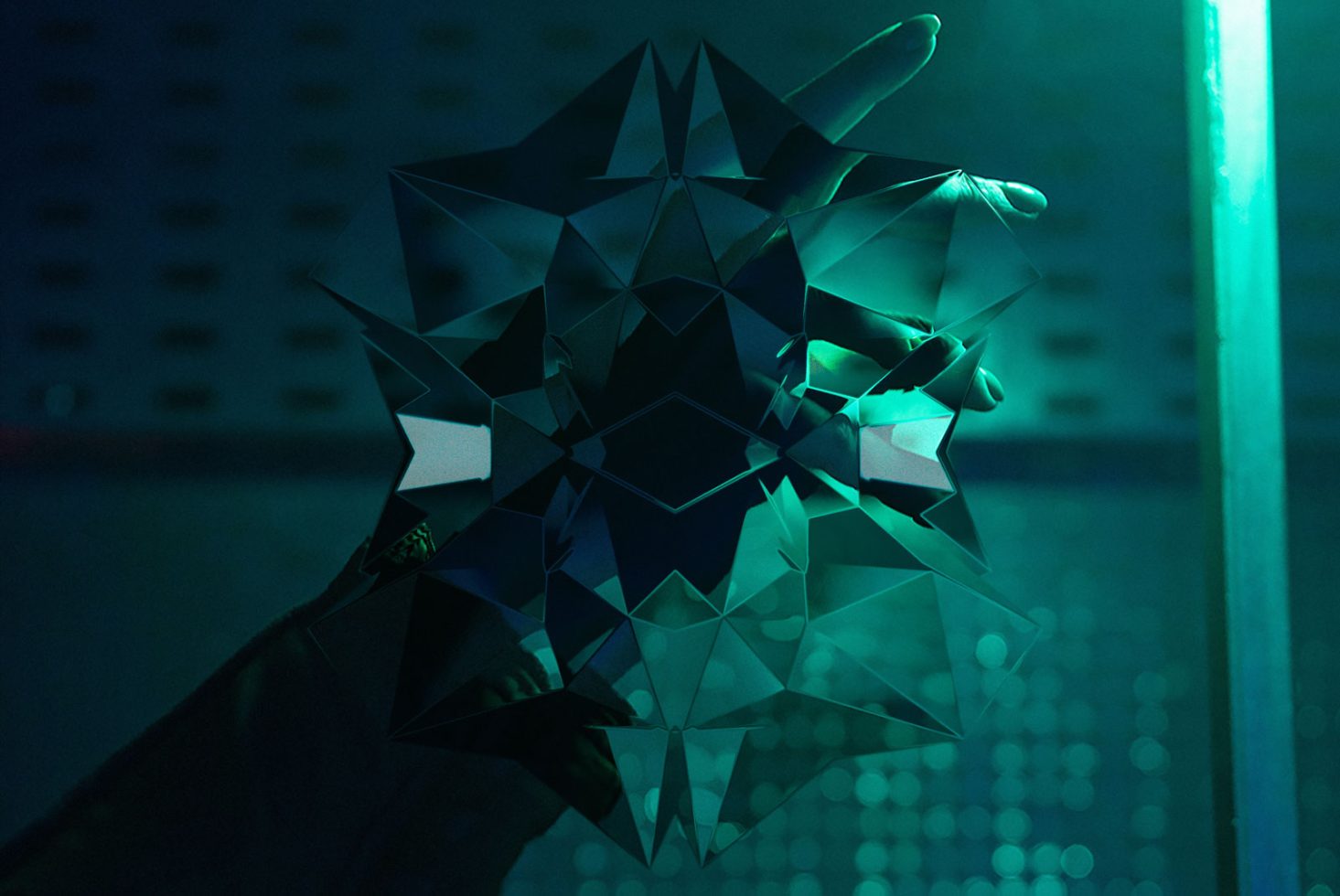 Complex geometric low-poly mask design in teal lighting, ideal for digital art, graphics inspiration, or 3D mockup template.