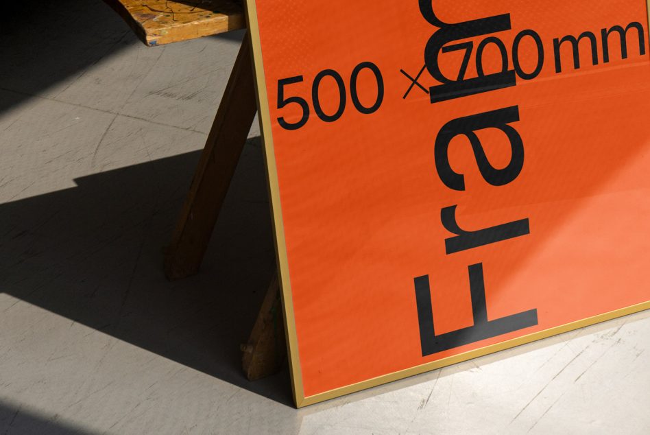 Bold typography design on orange poster displayed on easel, modern font, creative graphic print, designer workspace lighting.