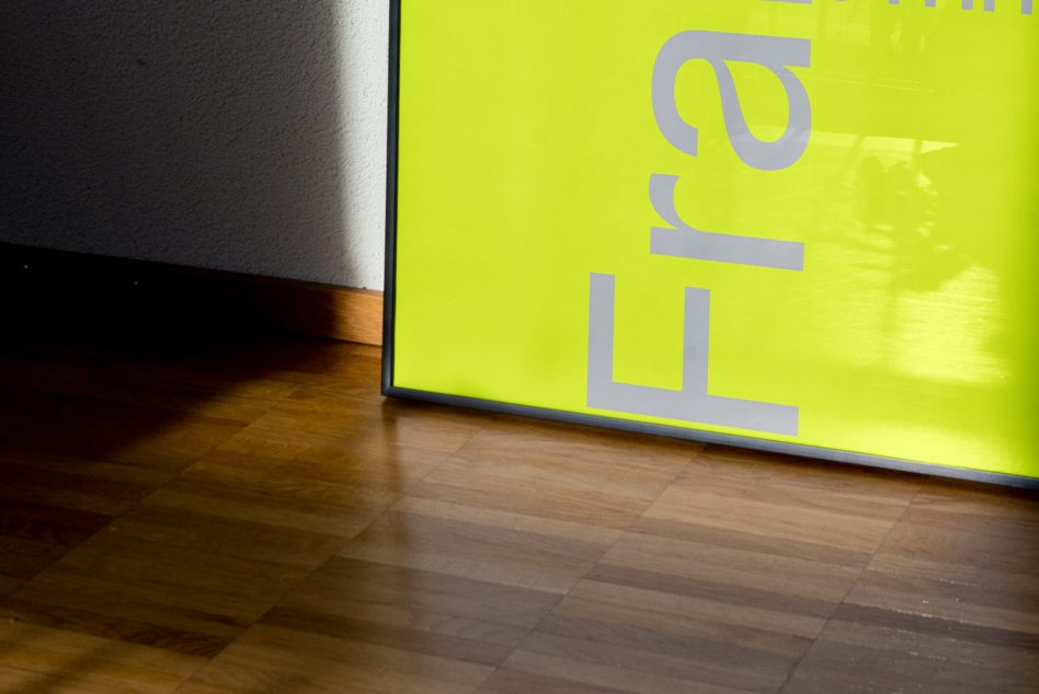 Bright yellow poster mockup leaning on wall with reflective wooden floor showcasing font and reflection, ideal for graphic design presentations.