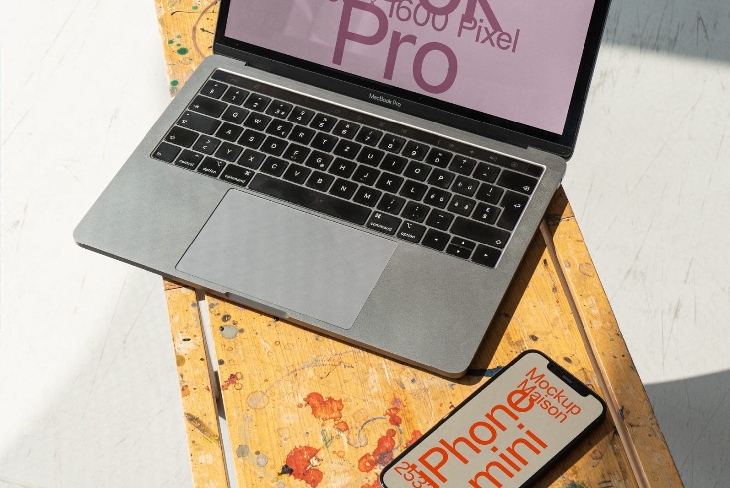 Laptop mockup on wooden table with smartphone template next to it, angled view in sunlight, useful for digital design presentations.