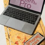 Laptop mockup on wooden table with smartphone template next to it, angled view in sunlight, useful for digital design presentations.