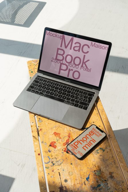 MacBook on distressed wood with iPhone mini beside it, mauve screen visible