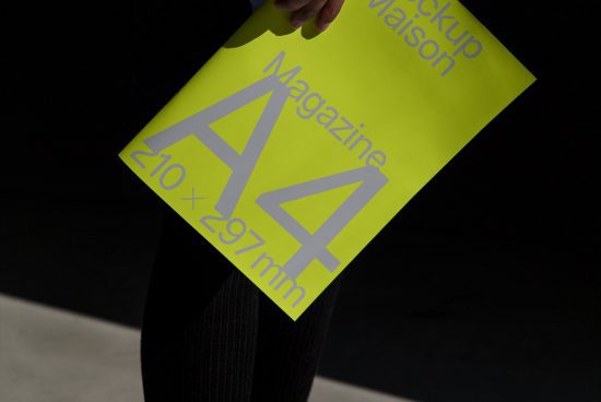 Person holding bright yellow magazine mockup with visible dimensions, ideal for graphic design presentations and portfolio showcases.