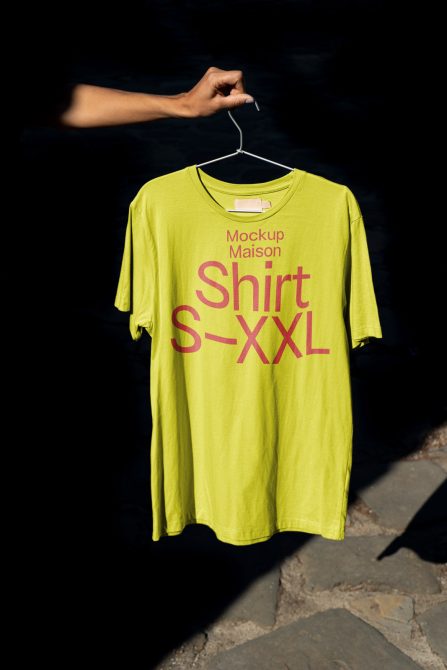 Chartreuse shirt on hanger with magenta text against dark backdrop