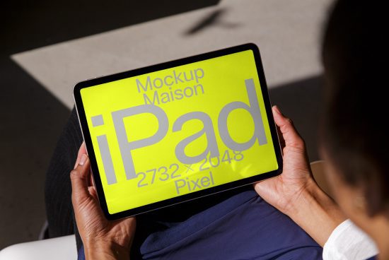 Person holding a tablet displaying digital iPad mockup template in bright yellow, resolution 2732x2048 pixels, ideal for designers' presentations.