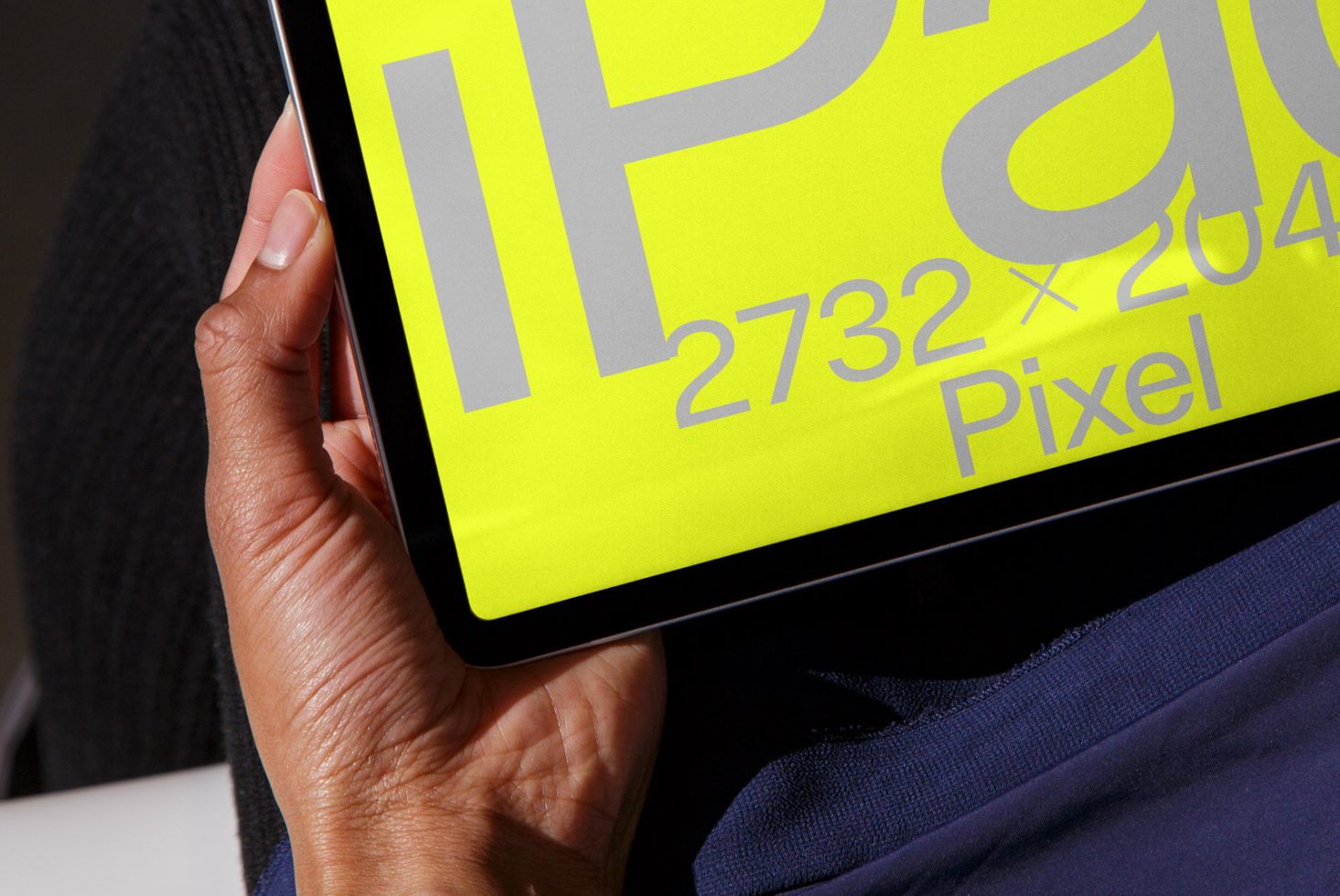 Person holding a tablet showcasing a bold font with dimensions, ideal for designers eager for trendy mockups or typography inspiration.