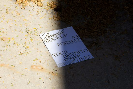 A4 paper mockup with custom text lying on concrete surrounded by scattered leaves, highlighting design presentation.