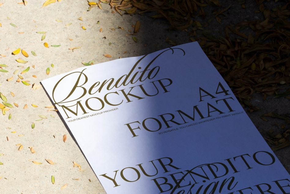 Blue A4 bendito mockup with foliage scattered on textured concrete surface