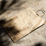 Paper bag mockup on textured ground with natural shadows, ideal for eco-friendly branding presentations and packaging designs.