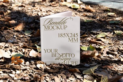 Book mockup in natural setting, showing a customizable 185x245 mm paperback cover surrounded by autumn leaves, perfect for graphic design presentations.