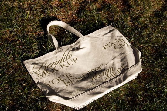 Eco-friendly tote bag mockup on grass for design presentation, showcasing customizable fabric texture and sunlight shadow overlay, ideal for product branding.