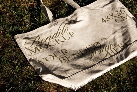 Canvas tote bag mockup on grass showcasing custom script font design with editable text, ideal for presentations in graphics category.