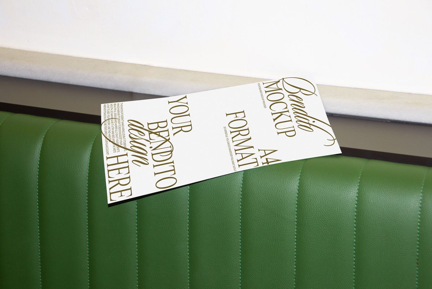 Mockup of a flyer with elegant typography leaning on a green leather sofa for design presentation.