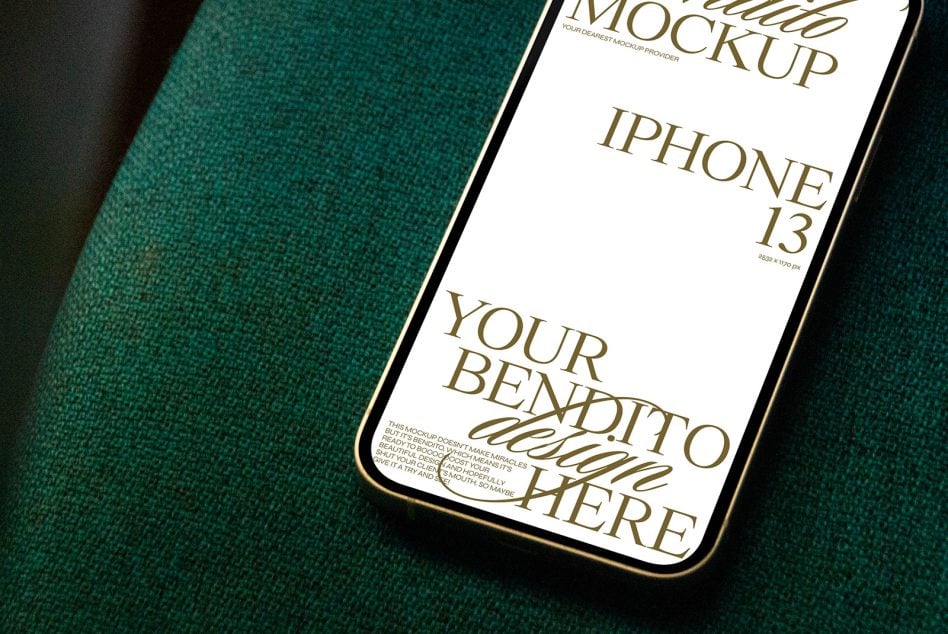 iPhone 13 on deep teal textured fabric with gold trim detail