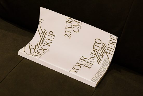 Magazine mockup on black sofa featuring customizable cover for design presentation, 23x30 cm size, graphic design template.