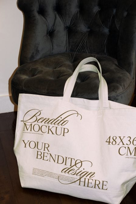White tote bag sitting on black quilted chair, gold text visible on front
