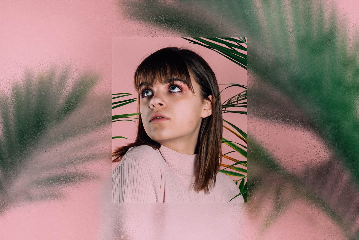 Creative portrait mockup with tropical plant shadows, female model with bangs, and a pastel pink textured background for design assets.