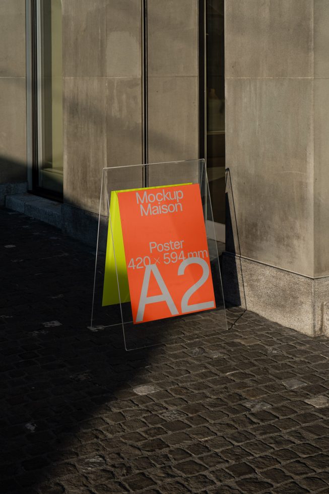 Urban poster mockup in sunlight on a sidewalk against a building for designers to showcase advertisements, prints, or graphics.