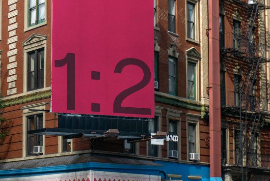 Urban billboard mockup with ratio 1:2 on a vibrant pink background set against an old building facade, ideal for showcasing ad designs.