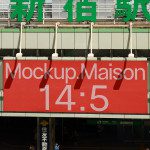 Red billboard mockup with stylized text 'MockupMaison 14:5' for outdoor advertising display, urban setting with passing train in background.