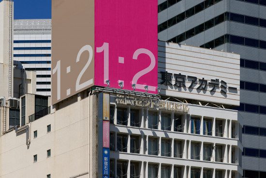 Urban billboard mockup with large numbers on a pink background, flanked by Japanese text, ideal for design display in cityscape settings.