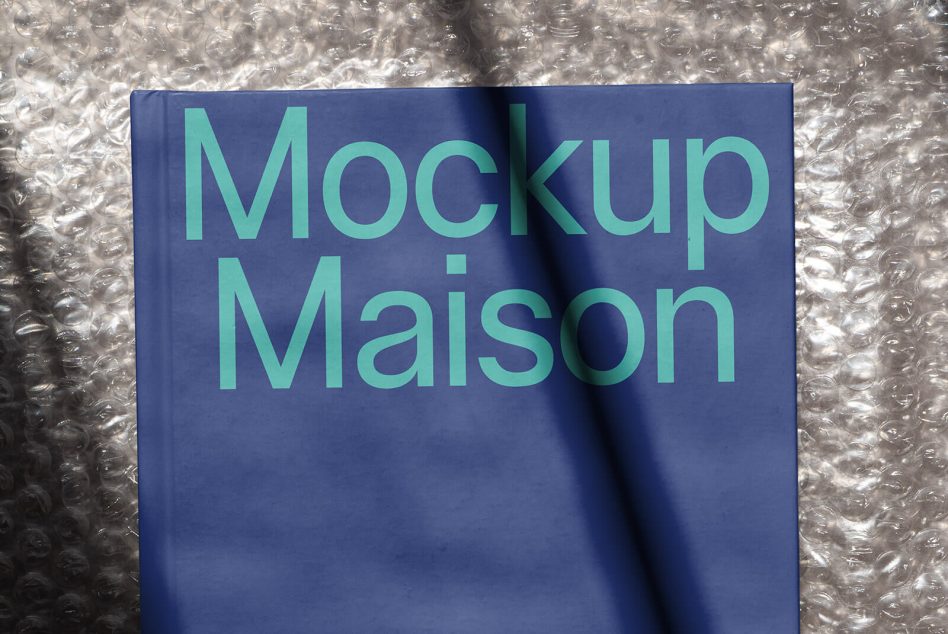 Blue book cover mockup with the title Mockup Maison on bubble wrap background for graphic design and presentation material.