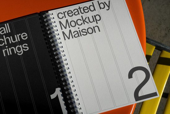 Spiral notebook mockup on orange surface with industrial background for graphic designers, showcasing page layout and binding design.