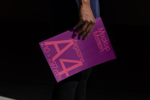 Person holding a purple magazine mockup with text design, demonstrating a realistic print template for graphic designers.