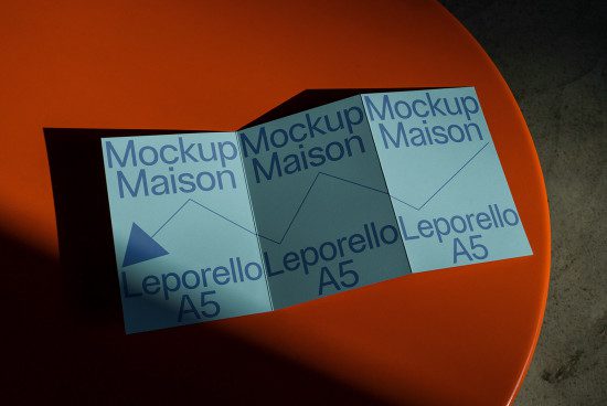 A5 Leporello brochure mockup on orange surface, print design presentation, realistic foldable brochure, graphic design asset.