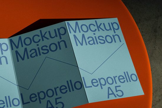 Printed paper mockup on orange surface showcasing design presentation. Graphic design, layout mockup, A5 print, blue tones, realistic texture, designer asset.