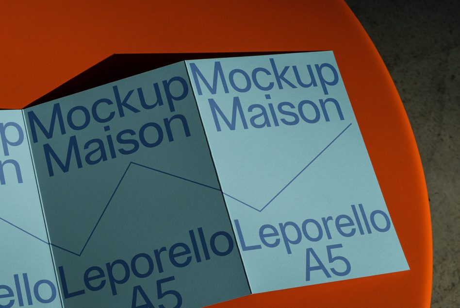 Folded A5 leaflet mockup on bright orange background showing teal paper with blue text