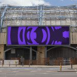 Urban billboard mockup displaying purple abstract design, set against a modern building facade, ideal for designer presentations.