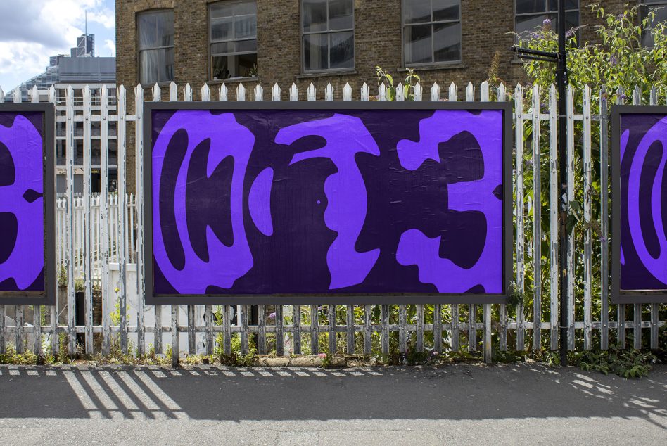 Wide purple display behind weathered fence with cloud sky backdrop