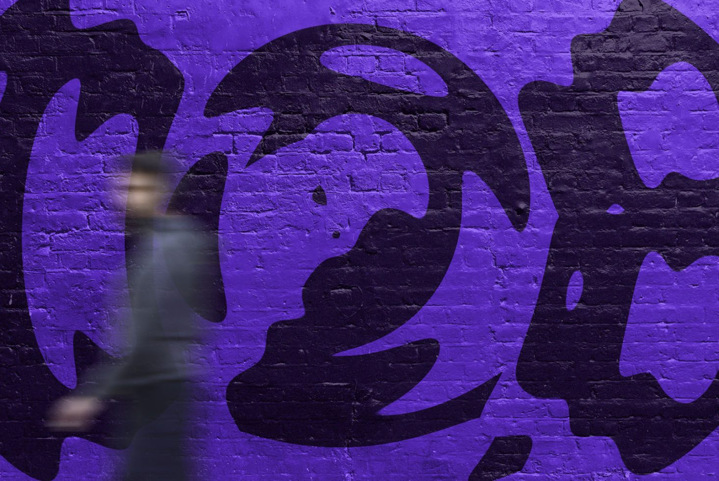 Dynamic blurred figure walking past a vivid purple graffiti wall, urban street art for graphics and templates design inspiration.