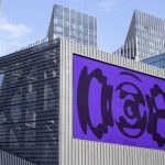 Urban billboard mockup on modern building facade with dynamic abstract purple graphic design for advertising and branding presentation.